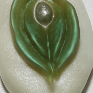 A green leaf shaped soap sitting on top of a white surface.