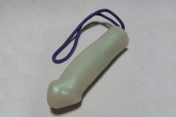 A white plastic toy with purple string on top.
