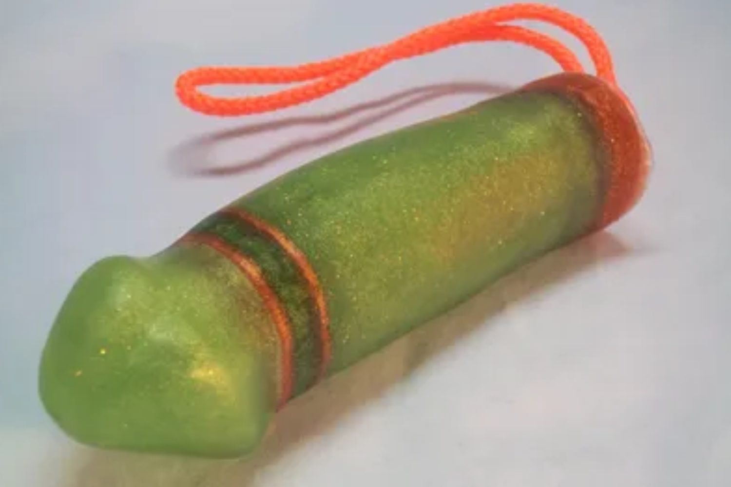 A green toy with orange string hanging from it.