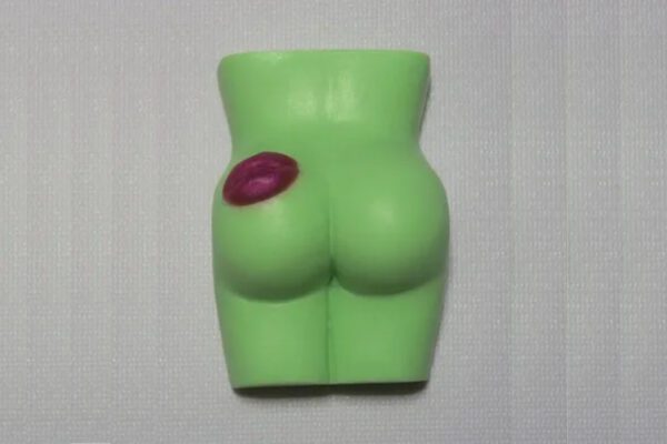 A green butt toy with a red lip on it.