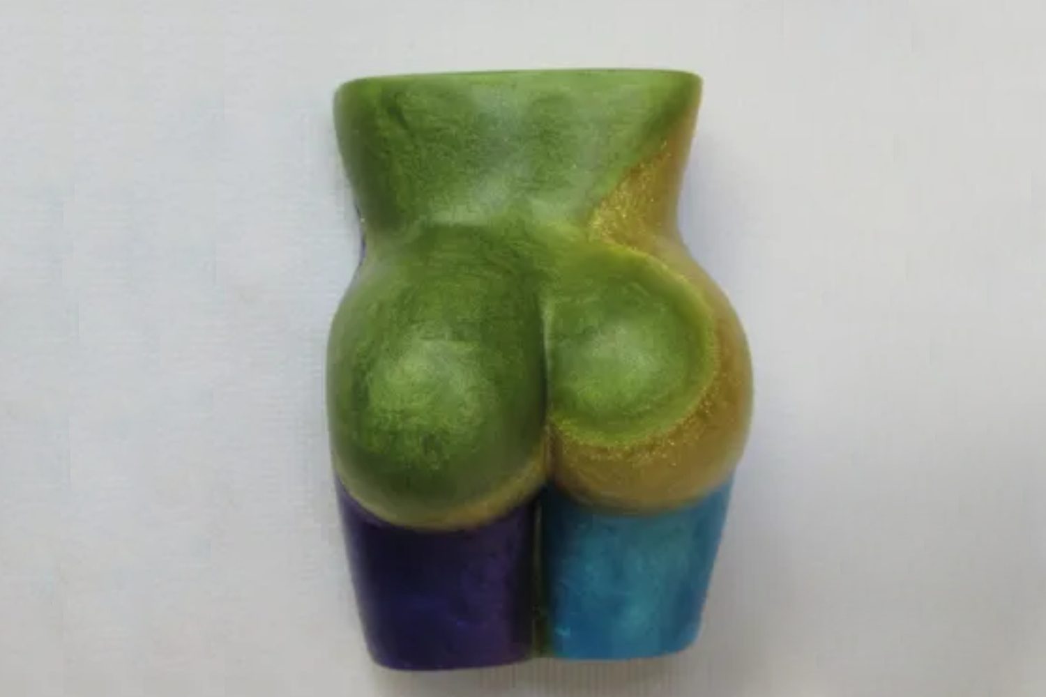 A green and blue butt sculpture on top of a white surface.