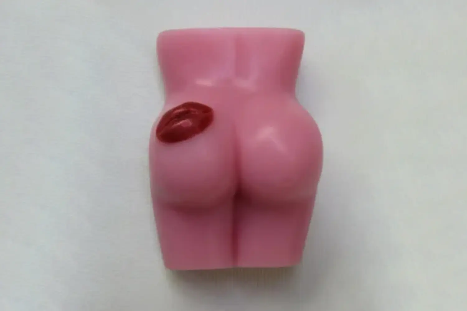 A pink soap shaped like a woman 's butt and lip.