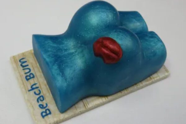 A blue cake with two breasts and one red lip.
