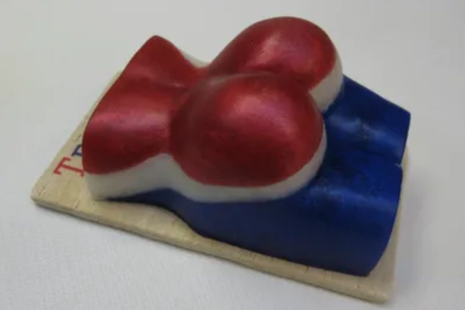 A red, white and blue soap on top of a wooden board.