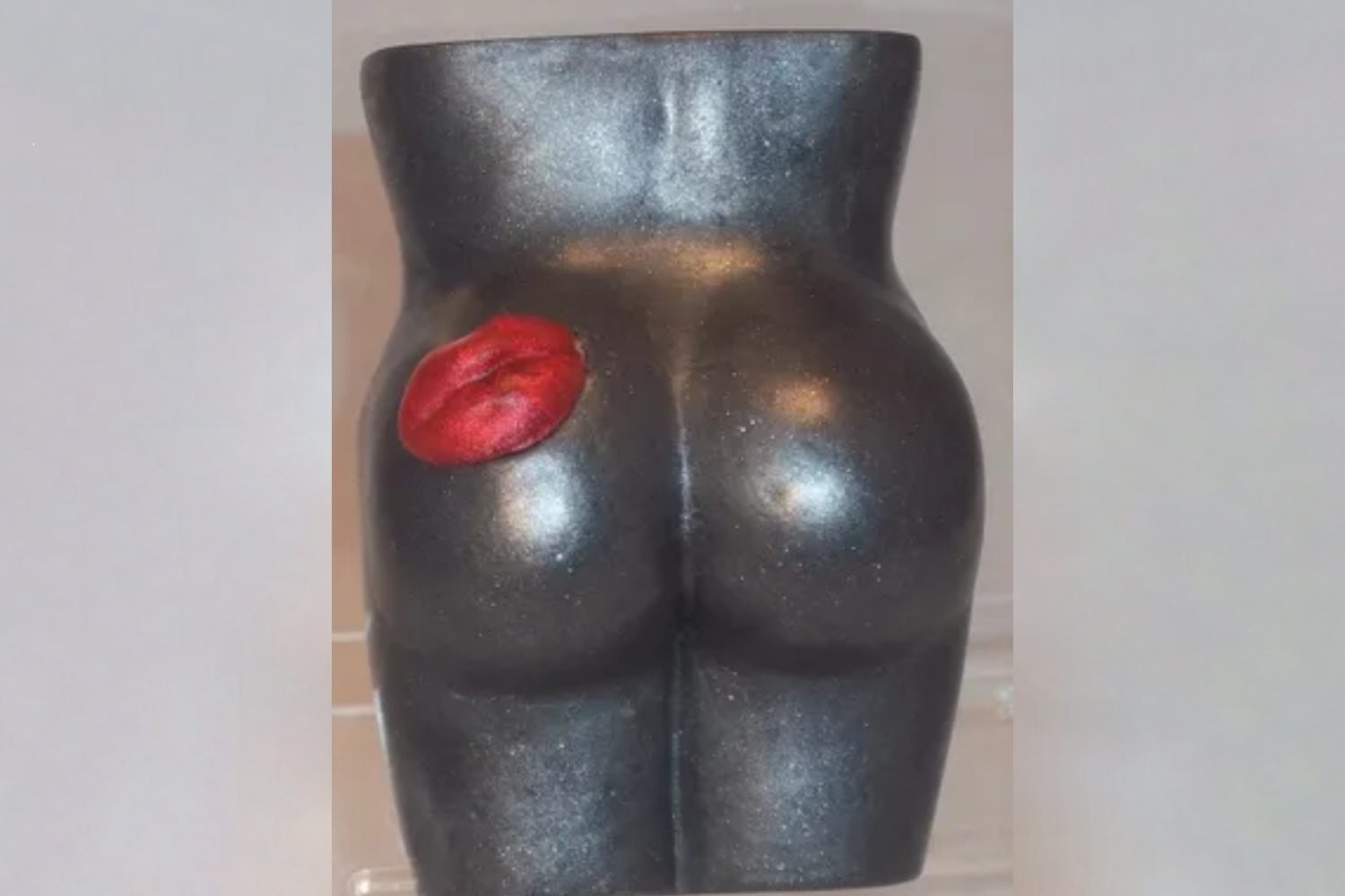 A black statue of a woman 's butt with red lips.