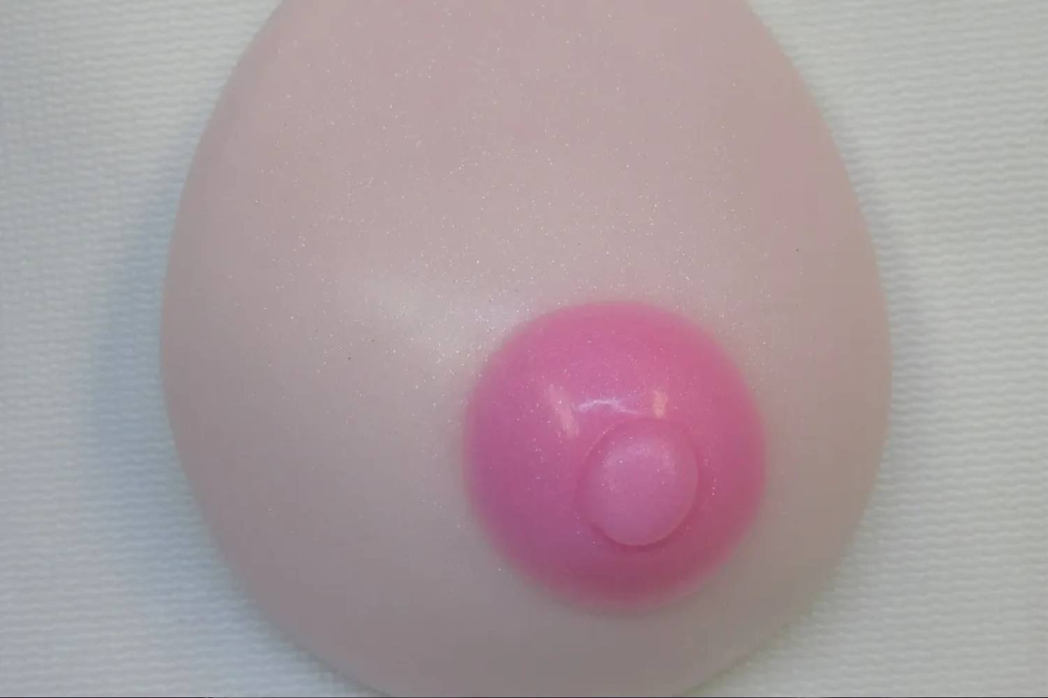 A pink breast implant is shown on the side of a wall.