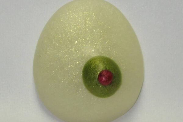 A close up of an egg with a green and red eye.