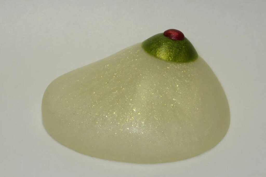 A white piece of food with green and red accents.
