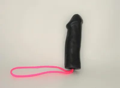 A black rubber glove with pink cord attached to it.