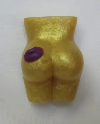 A gold colored butt with purple lips on it.
