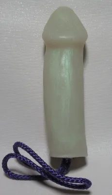 A white candle with purple cord on top of it.