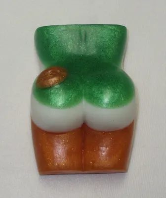 A green and white butt shaped candle on top of a table.