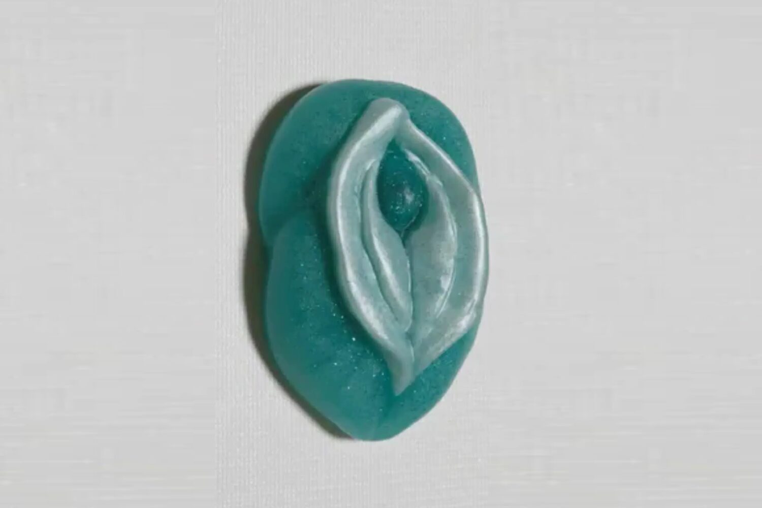 A blue and white button with an image of a woman 's breast.