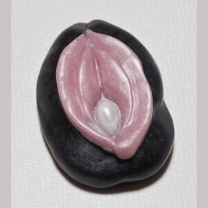 A black and white pin with pink clay on it