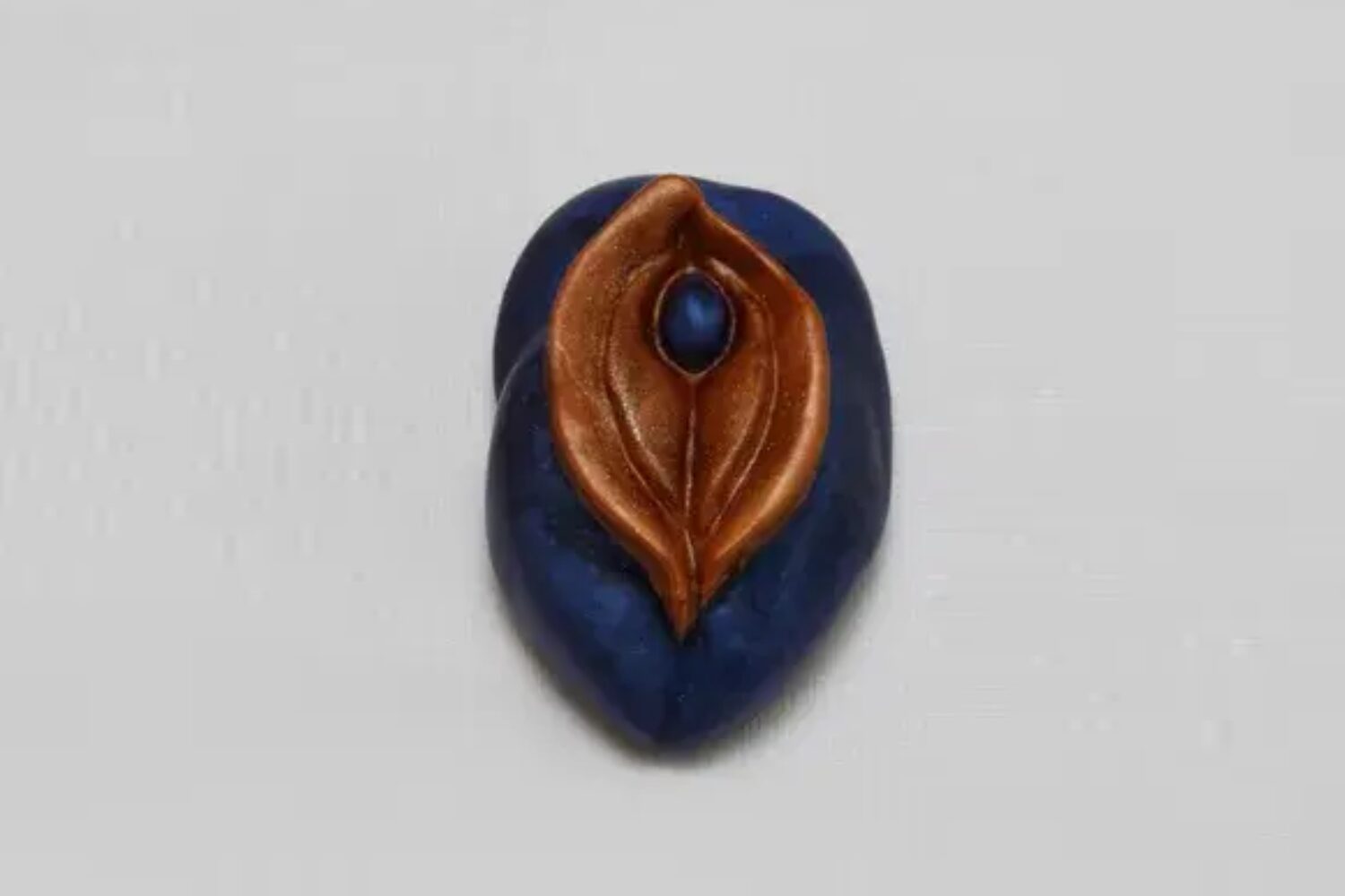 A blue and brown leaf with a small blue bead.