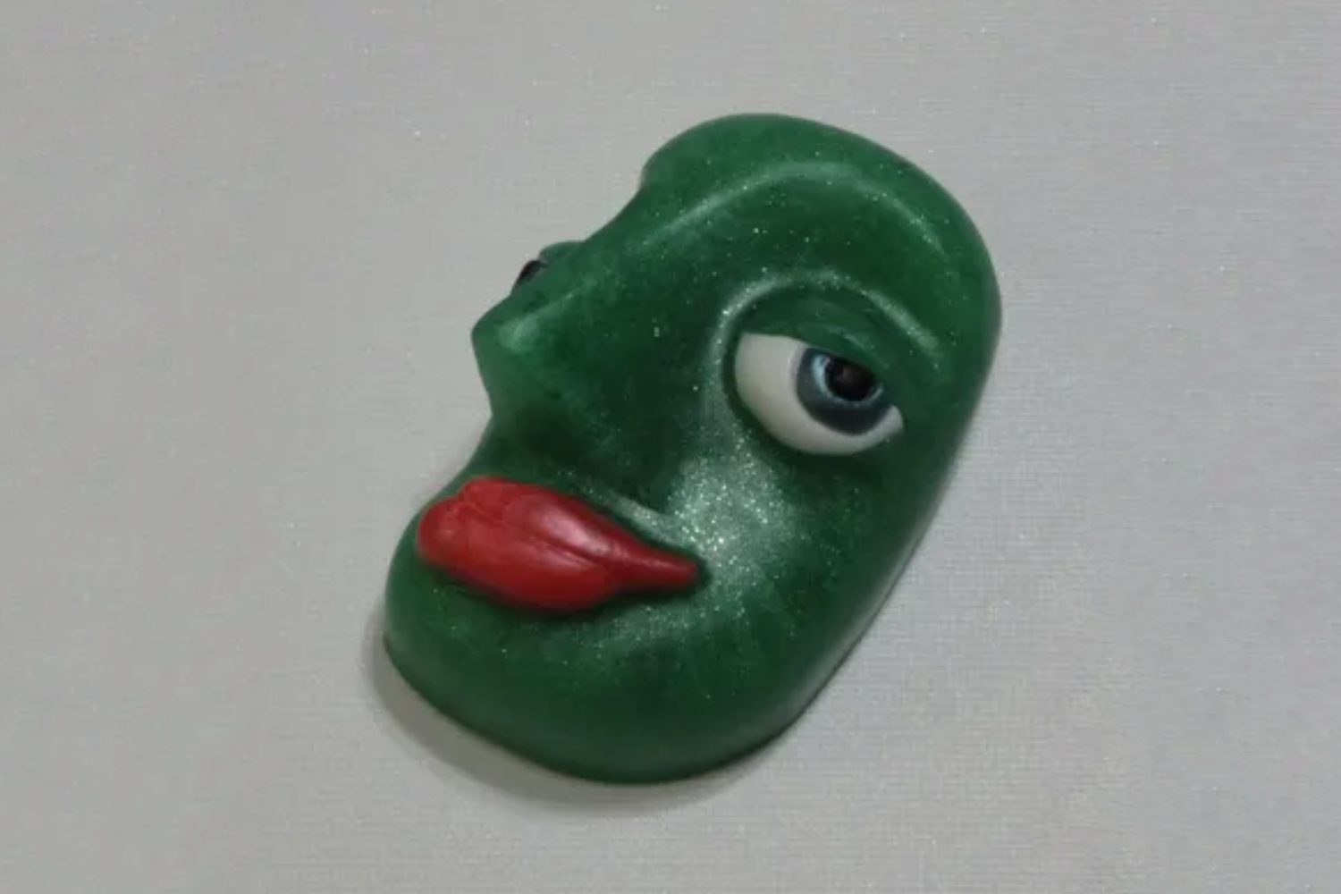 A green face with red lips on top of it.