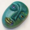A green face with blue eyes and yellow lips.