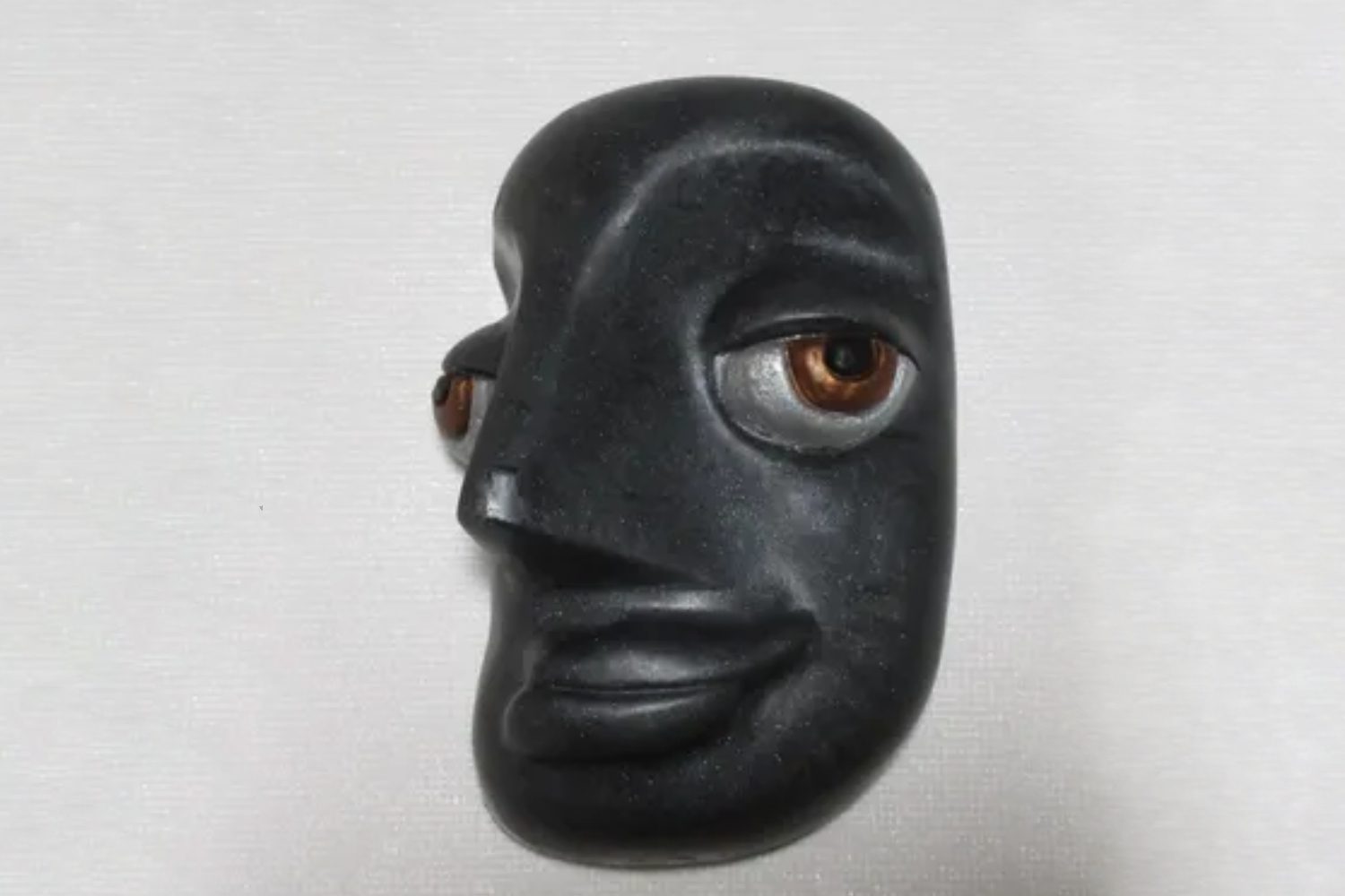 A black face with brown eyes and a nose.