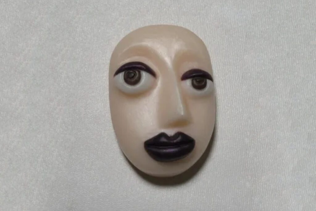 A white face with black lips and brown eyes.