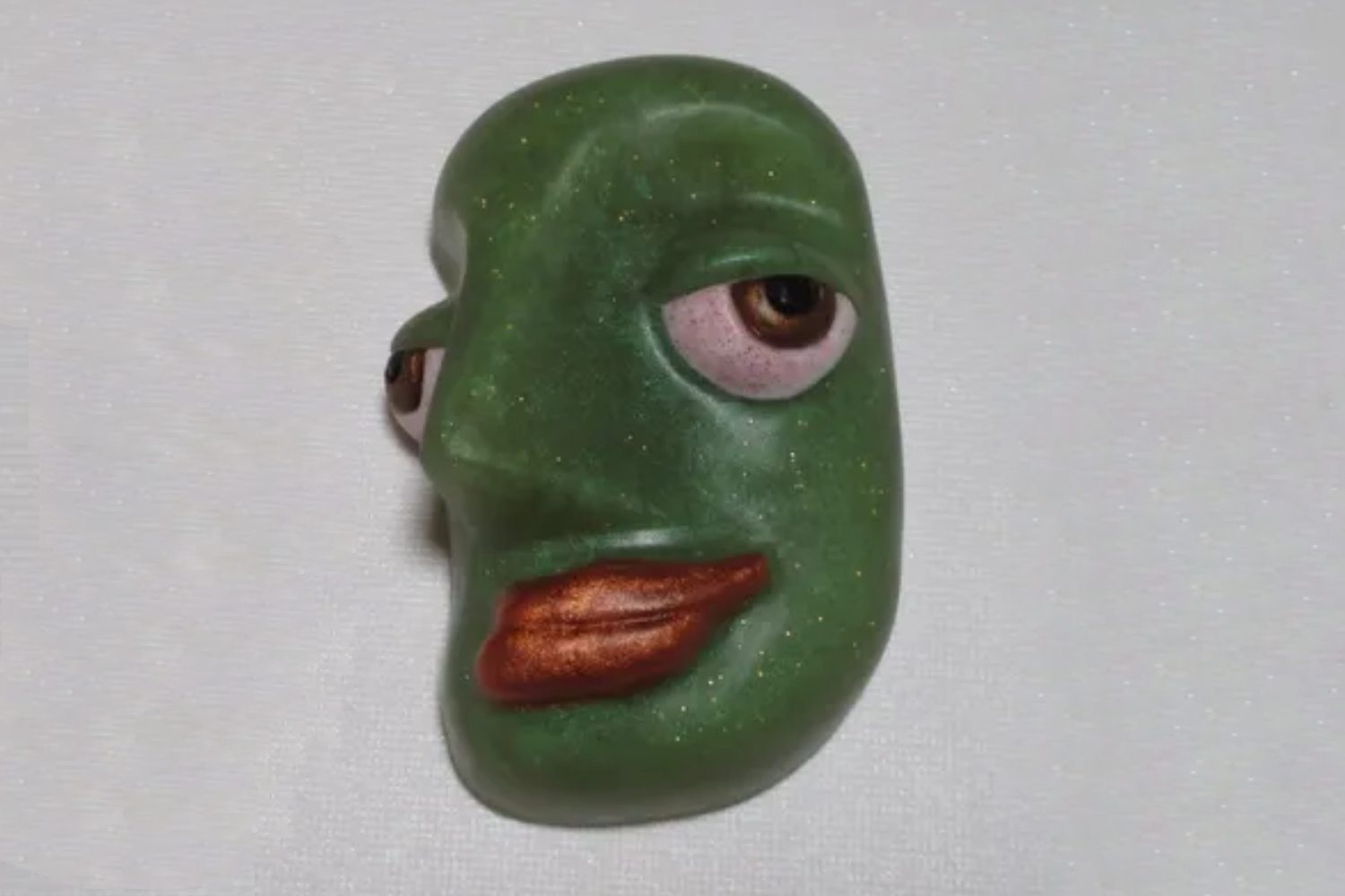 A green face with brown eyes and red lips.