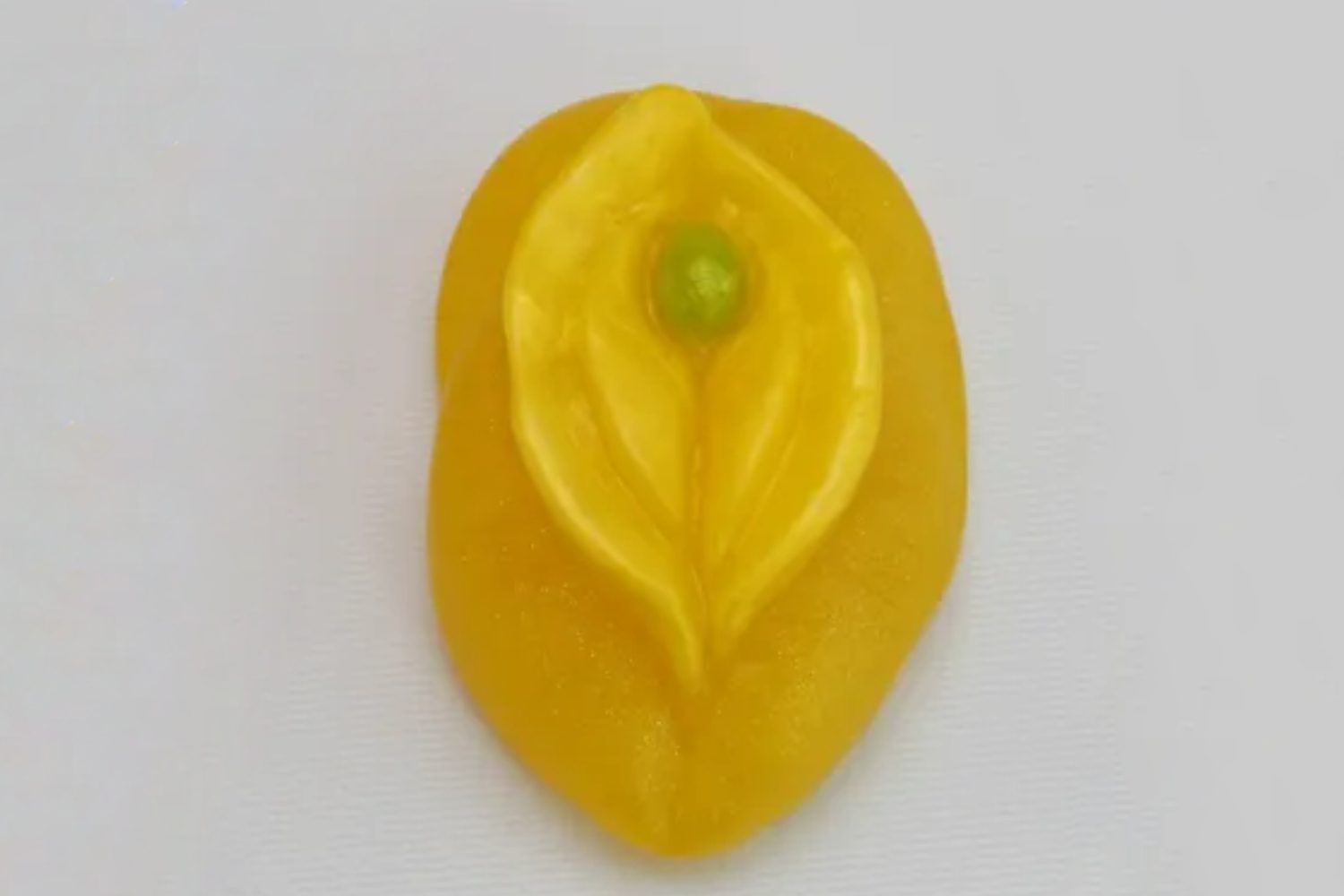 A yellow leaf with green bead on top of it.