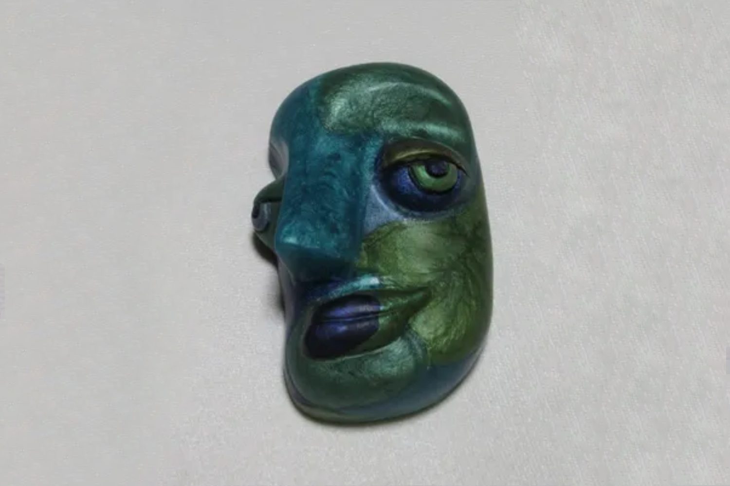 A green and blue face with eyes on it.