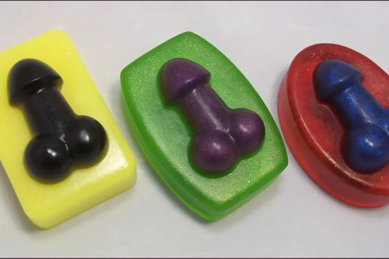 Three different colored soaps sitting on top of a table.