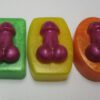 Three different colored soaps with a purple condom on top of them.