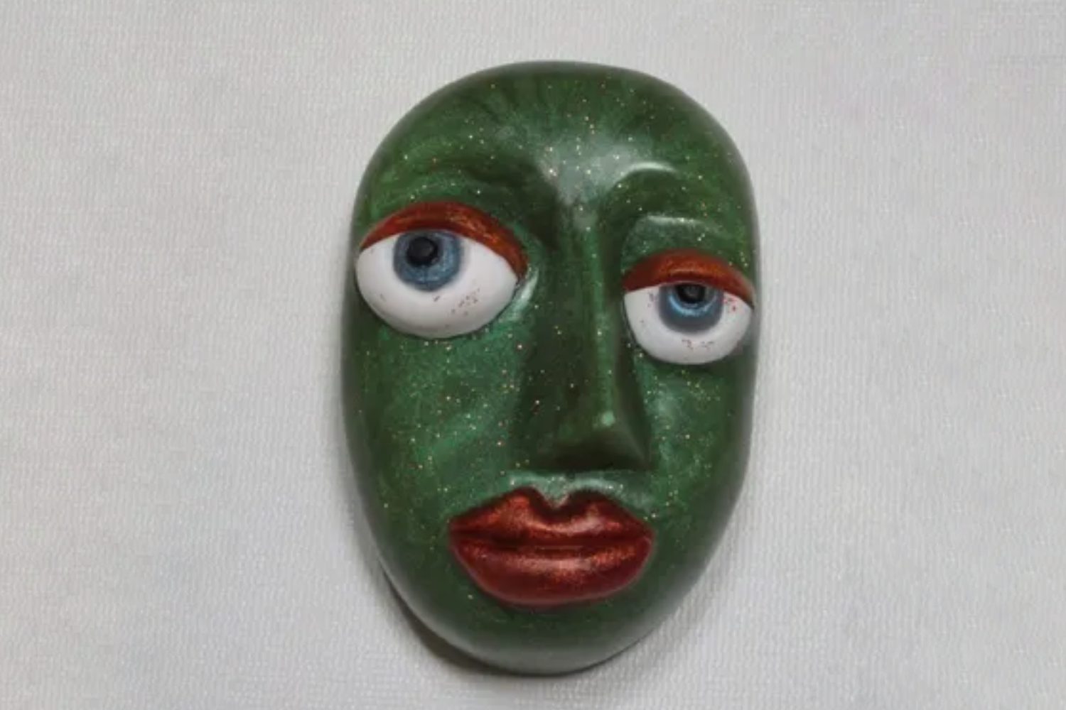 A green face with red lips and blue eyes.