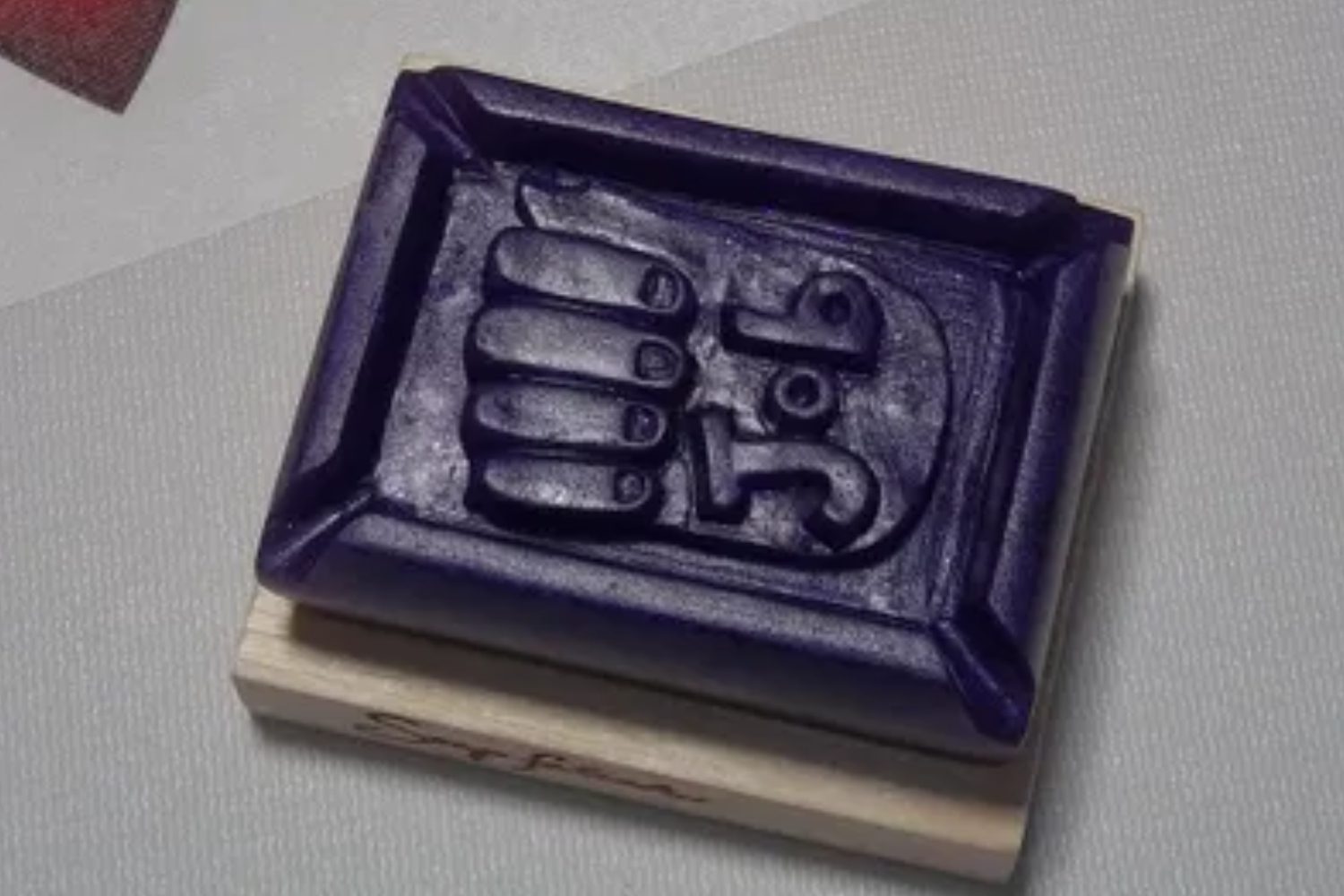 A purple rectangular object with a picture of a hand.