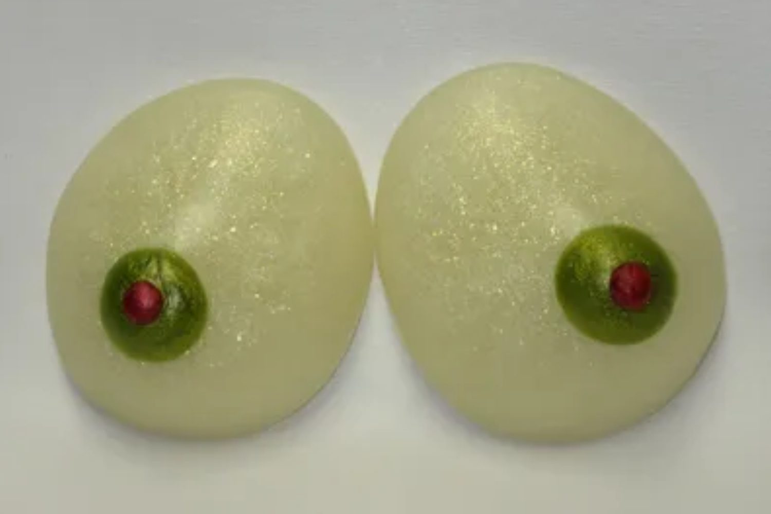 Two large white balls with green eyes on a table.