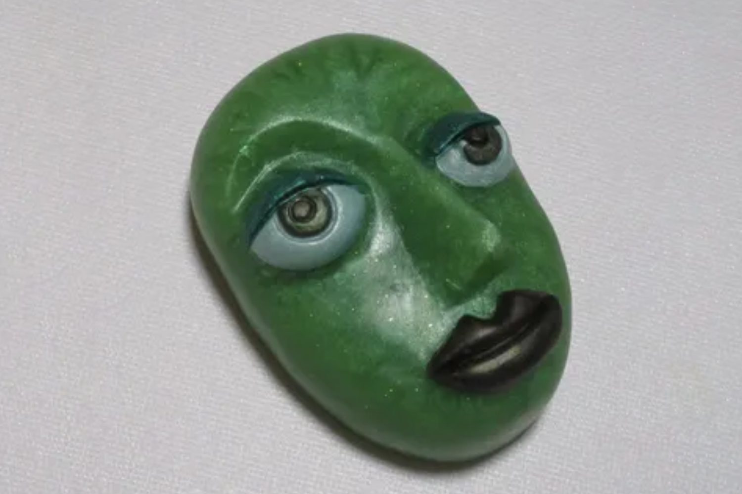 A green face with blue eyes and black lips.