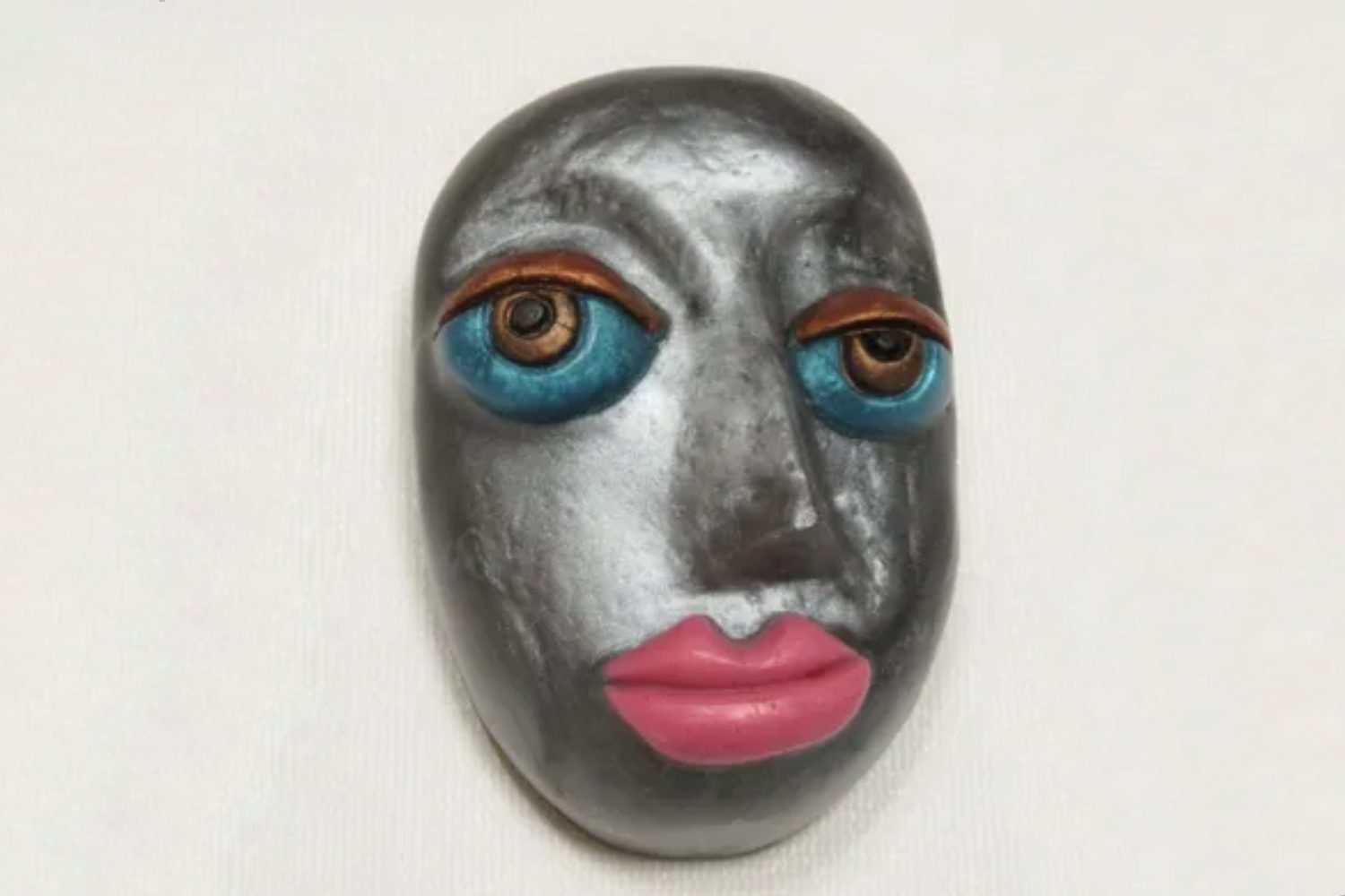 A silver face with pink lips and blue eyes.