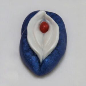A blue and white leaf with red bead on top of it.