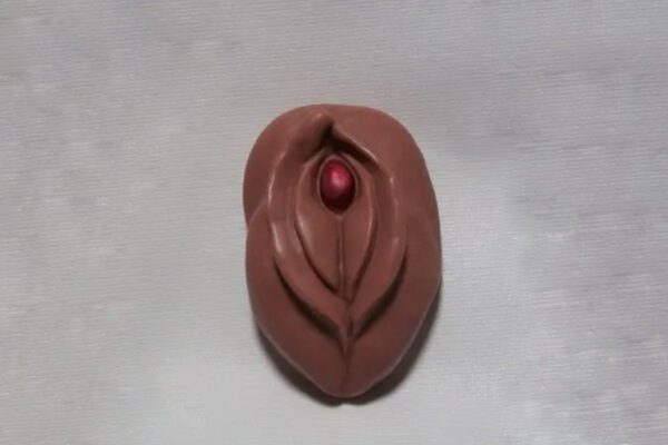 A chocolate sculpture of an egg shell with a red bead.