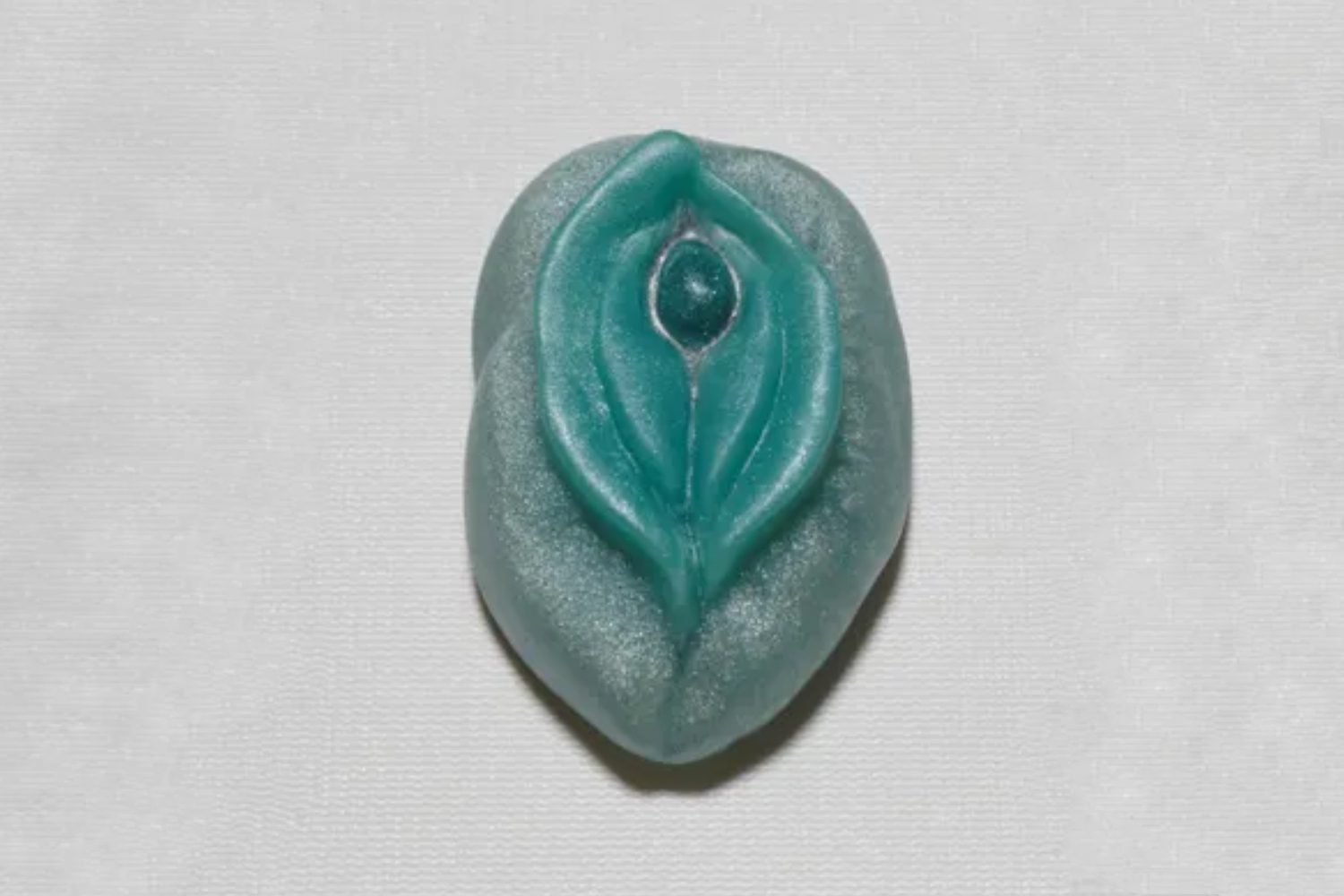 A green leaf shaped bead with a blue center.