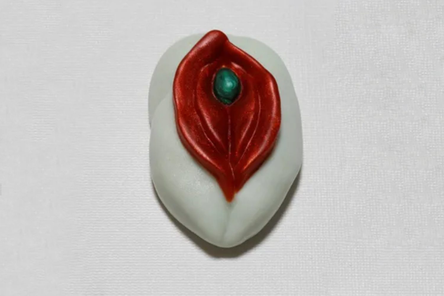 A white and red leaf with a green stone.