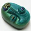 A green face with blue eyes and a nose ring.