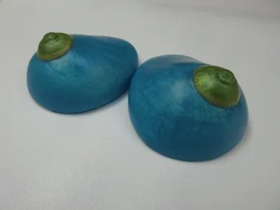 Two blue apples with green tops on a table.
