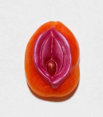 A close up of an orange with a pink and purple sex toy