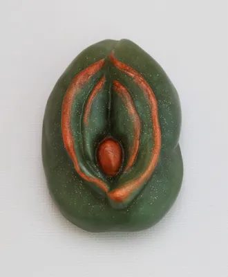 A green and red clay sculpture of a woman 's vagina.