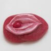 A pink jelly candy with a red lip on it.