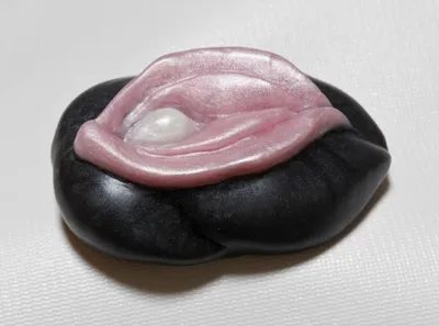 A black and pink stone with a white pearl in the middle.