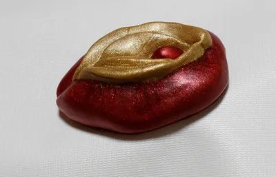 A red apple with a gold leaf on top of it.