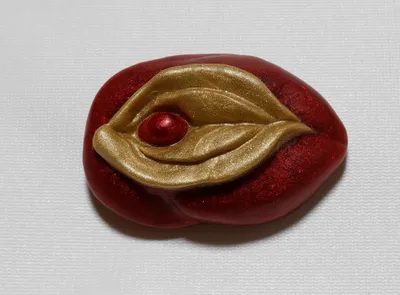 A red and gold leaf shaped object on top of a white surface.