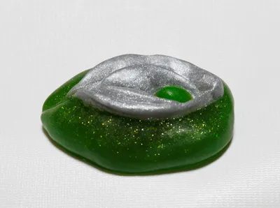 A green and silver jelly bean sitting on top of a table.