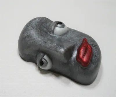 A grey face with red lips on top of it.
