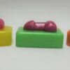 A row of different colored soap with a toy in the middle.