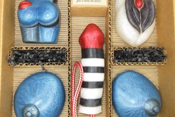 A box of chocolates with a red and black striped candle.