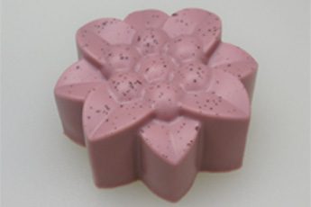 A pink flower shaped soap sitting on top of a table.